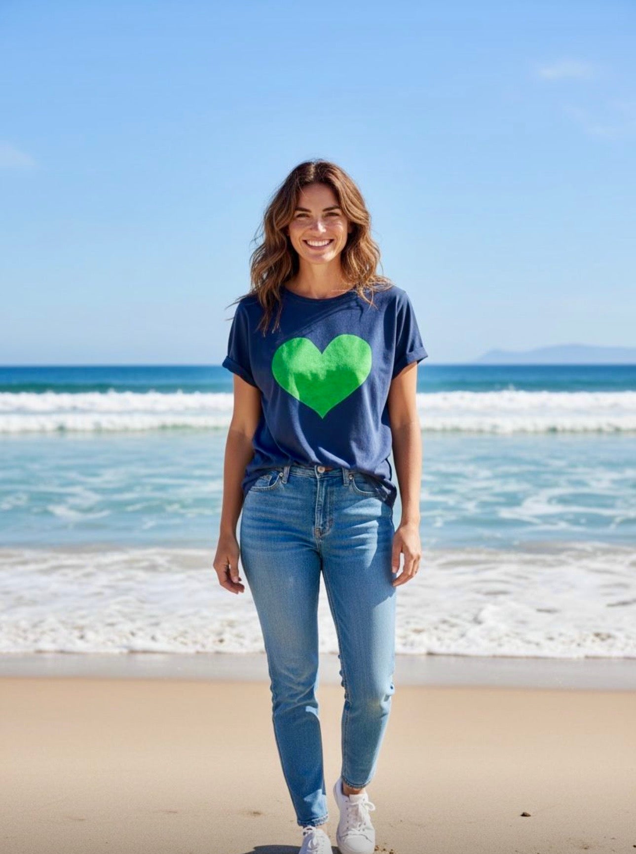 Woman wearing navy blue t-shirt with large green heart graphic on the front at the beach