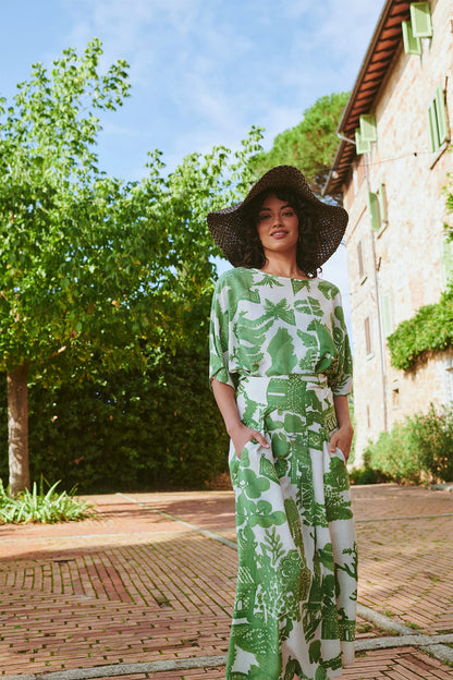 Woman wearing One Hundred Stars dress with green willow print and wide belt outside with large sun hat