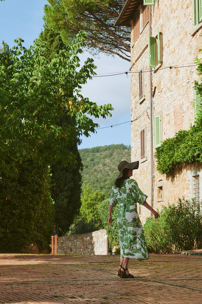 Woman photographed from behind walking outdoors wearing green willow print dress and large sun hat