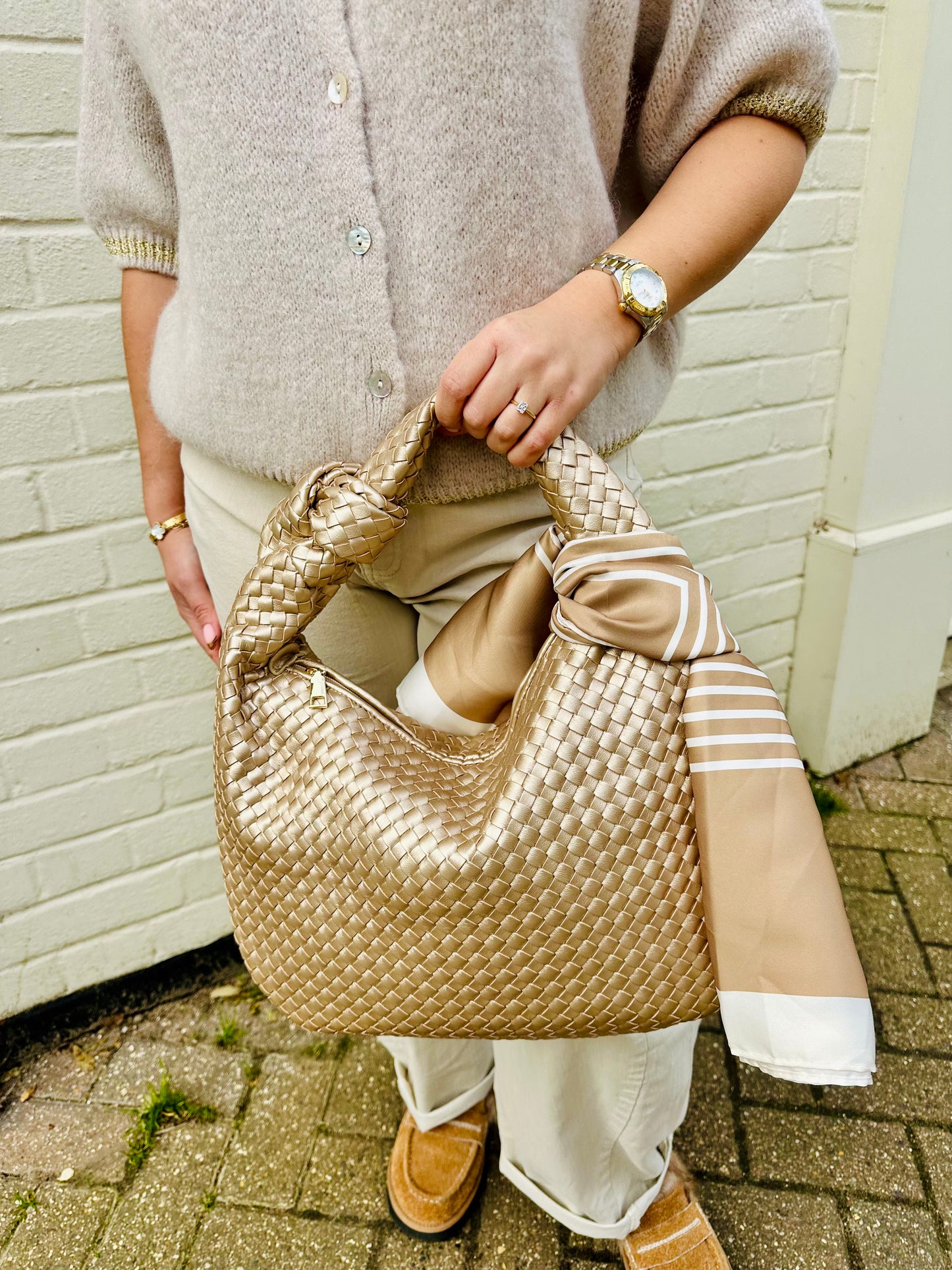 Taupe woven knot tote bag with a silk scarf accent held by a woman wearing neutral tones