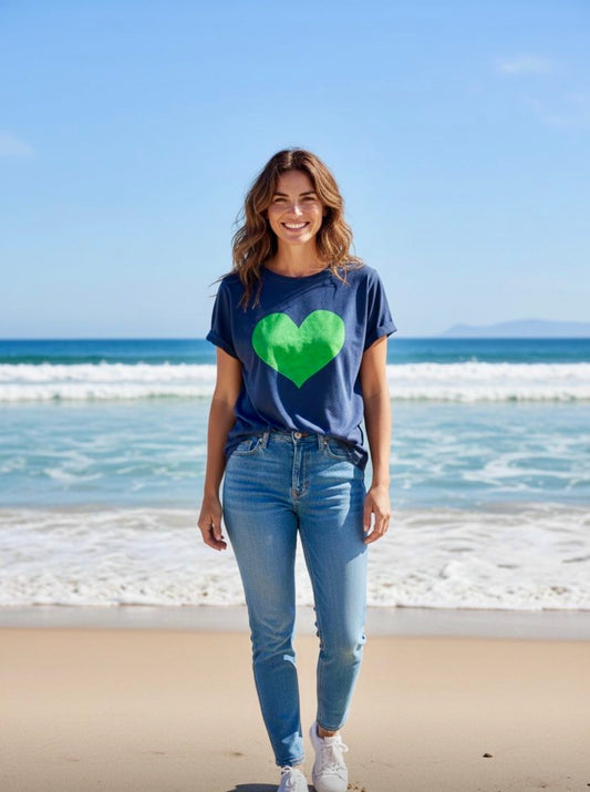 Woman wearing navy blue t-shirt with large green heart graphic on the front at the beach